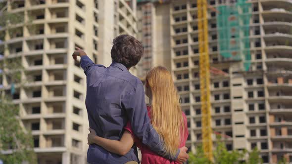 A Young Family Look at a Tall Building That is Under Construction