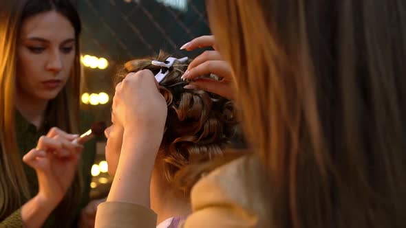 Hairdresser and Makeup Artist Doing Hairstyle and Makeup to Young Woman in Beauty Salon