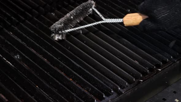 Man cleaning metal grill grate with brush