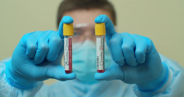 Competent Medical Worker in Protective Uniform Holding Test Tube with Blood for Analysis on COVID 19