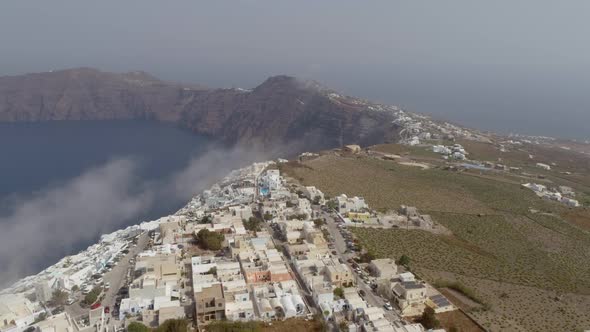 Aerial view of traditional white houses on Santorini island on cloudy day.