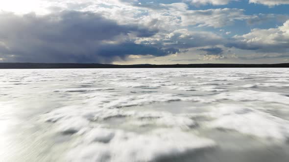 Drone Flying Fast Low Above Melting Glacier or Ice Cover of Winter Mountain Lake