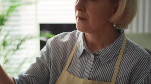 Tracking video of senior woman painting at easel. Shot with RED helium camera in 8K.