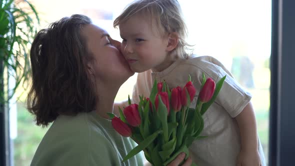 Boy Gives His Mother a Bouquet of Pink Tulips Congratulations on Mother's Day