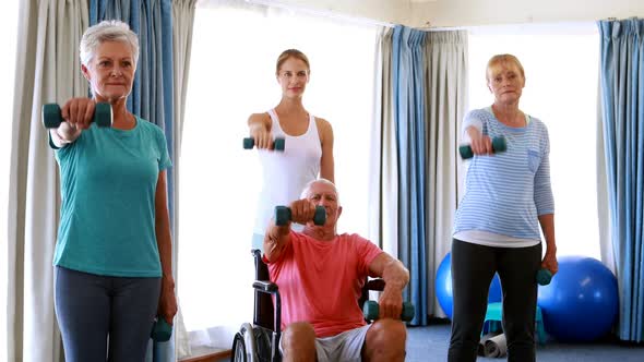 Trainer assisting senior citizens in performing exercise