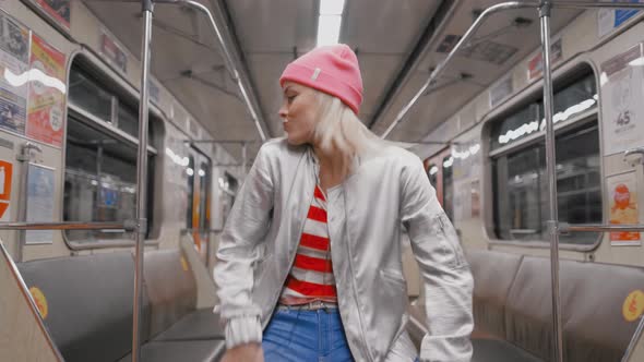 The Funny Attractive Joyful Blonde Girl Dancing in a Subway Car in Underground Metro. Woman Rejoices