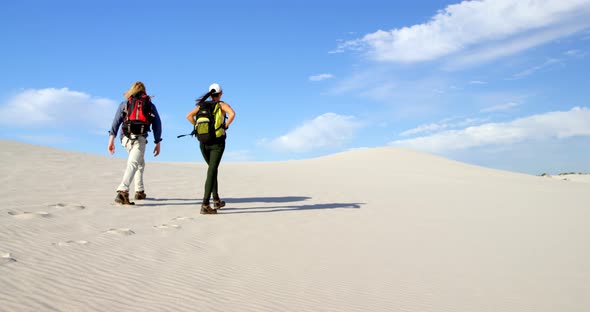 Couple with backpack walking in the desert 4k