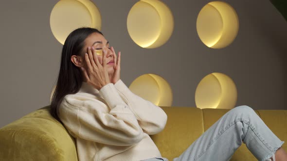 Young Asian Woman with Clear Radiant Skin with Moisturizing Golden Patches Under Her Eyes is Resting