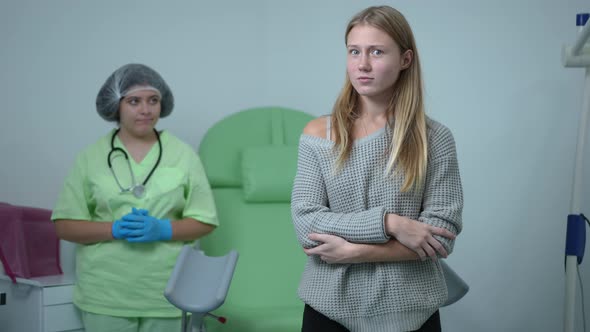 Scared Stressed Teenage Girl with Crossed Hands Looking Back at Gynecologist Standing at