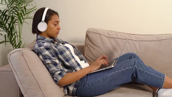 An AfricanAmerican Woman in Casual Clothes Works at Home Online with a Laptop