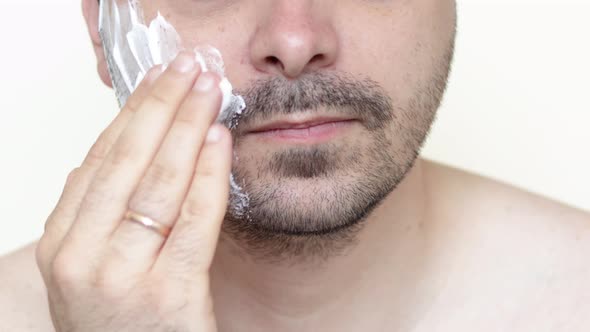 bearded man is applying shaving foam on face. skincare cosmetology concept.morning routine.bottom