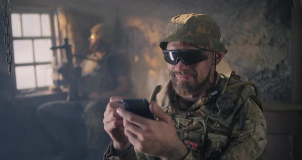 Military Man Using Smartphone Inside Grungy Building