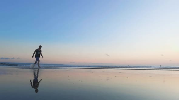 Man Walks on Beach in Low Tide with Reflections