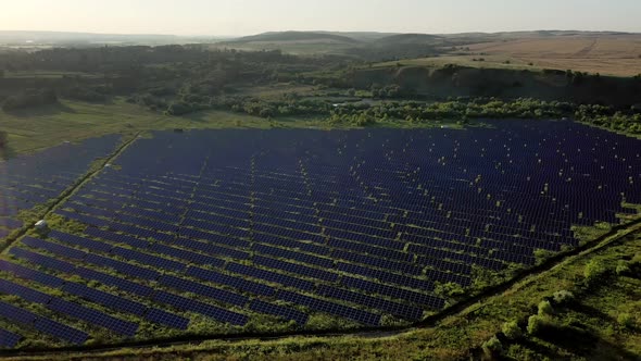 Aerial Top view on Solar Power Station in Green Field on Sunny day. Drone fly over Solar Farm.