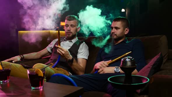 Two Young Men Smoke From Shisha Pipe