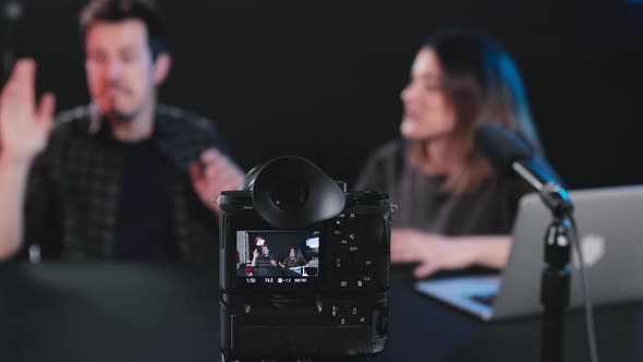 Happy male and female bloggers recording video on camera in studio