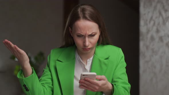 Indignant Woman Reads Unpleasant News on Smartphone in Room