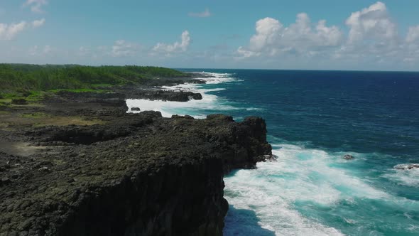 Aerial Top View of Waves Break on Rocks in a Blue Ocean