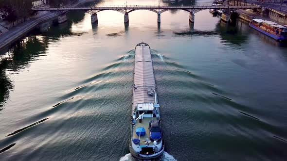Cargo ship floating on calm morning Seine river and heading to Pont des Arts. Tilting up camera foot