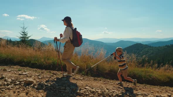 Woman and Child with Trekking Poles Hike Together Along a Rocky Path