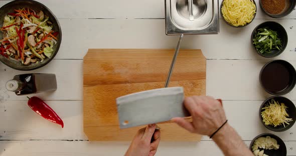 Chef's Hands Sharpen a Large Knife at the White Table on Working Ingredients