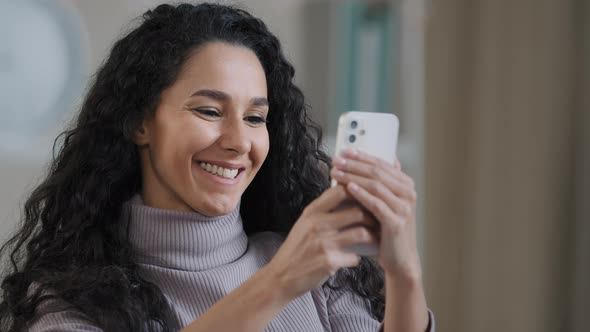 Close Up Portrait of Young Happy Hispanic Woman Holding Phone Browsing Social Networks Smiling