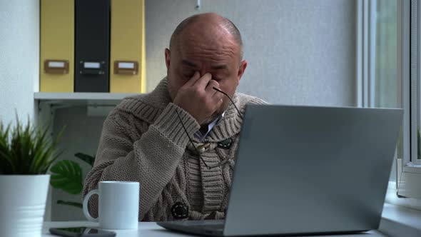 Tired Middle Aged Man in Eyewear Working with Computer Sitting at Home or in Office