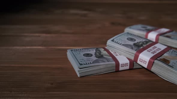 Three Stacks of 10000 American Dollars Banknotes in Bundles Lie on Wooden Table