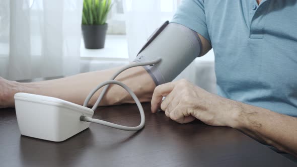 Elderly Man Measures His Own Blood Pressure with a Tonometer