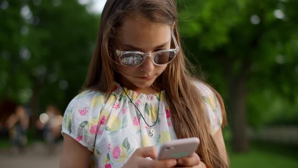 Close Up of Serious Girl Playing Games on Phone. Girl with Phone in Summer Park