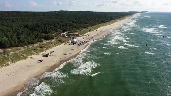 AERIAL: Rotating Shot of Surfers Riding Waves with Kites on a Sunny Day