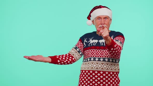 Grandfather in Santa Christmas Sweater Showing Thumbs Up and Pointing Empty Place Advertising Area