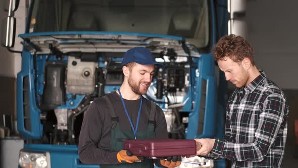 Young Automotive Technician Talking with Male Client