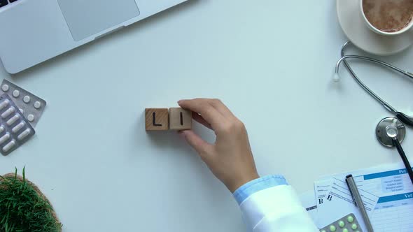 Life Word Composed of Wooden Cubes by Female Doctor Hand, Toy Heart Lying Near