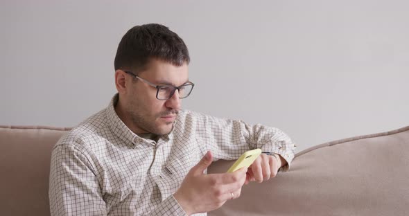 Man Sitting on Couch with Smartphone