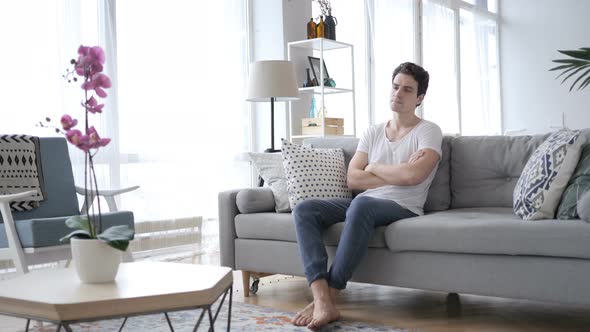 Serious Relaxing Man Sitting on Sofa at home