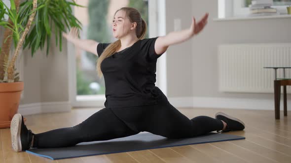 Side View Wide Shot of Charming Obese Young Woman Sitting in Twine Pose on Exercise Mat Doing