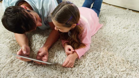 Father and daughter using digital tablet in the living room