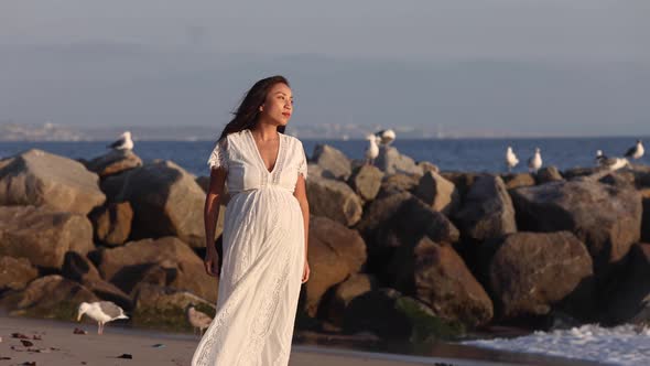 Pregnant Asian woman enjoying walk on the beach