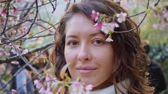 Closeup Portrait of Pretty Girl in Park with Blooming Japanese Sakura Trees