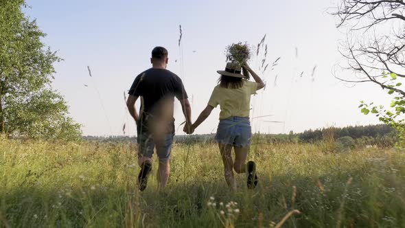 Happy Middle Aged Couple Running Together Holding Hands Back View