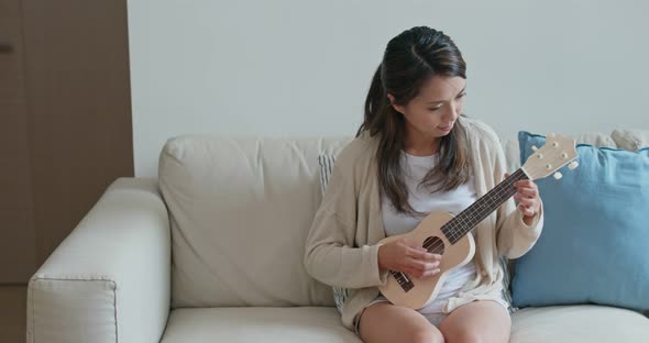 Woman play ukulele at home