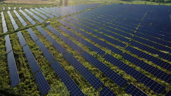 Aerial Top view on Solar Power Station in Green Field on Sunny day. Drone fly over Solar Farm.