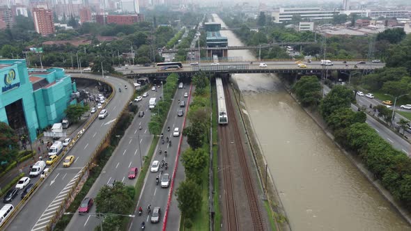 view of the medellin metro leaving the station next to the highway and the river