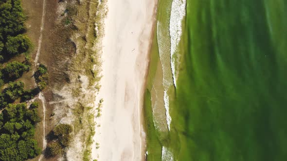 AERIAL: Flying extremely high over the sunny sandy beach