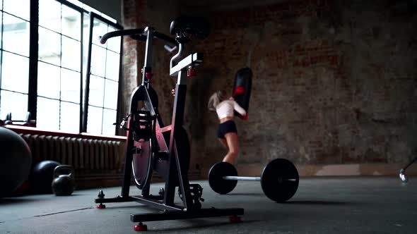 Sexy Lady Is Training in Gymnastic Hall, Striking on Punching Bag By Hands, Sporty and Active