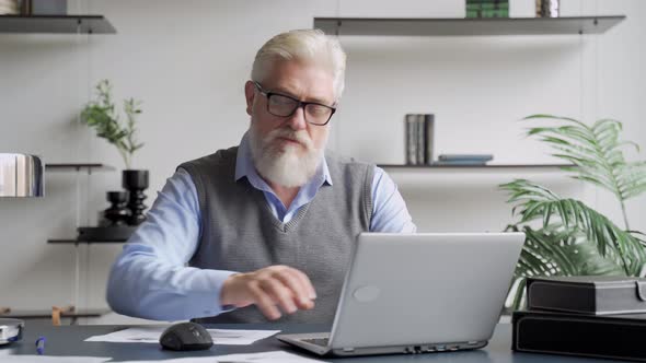 Bearded Senior Man Working with Laptop in Office