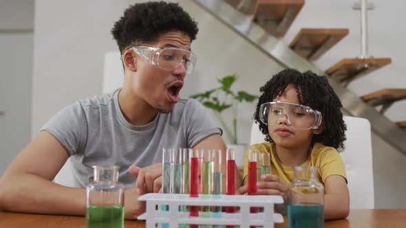 Happy biracial man and his son making chemistry experiments