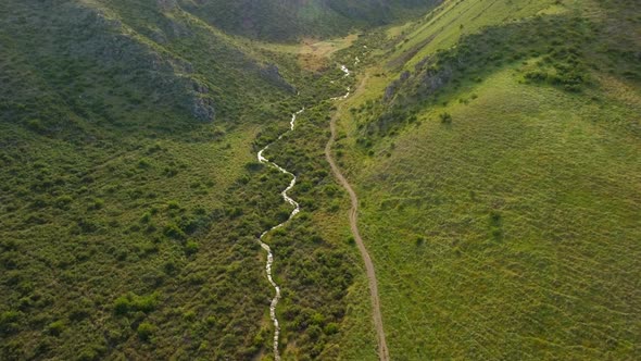 Winding river and road between green hills