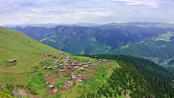 Flying Nearby Small Highland Village Among Beautiful Mountain Expanse